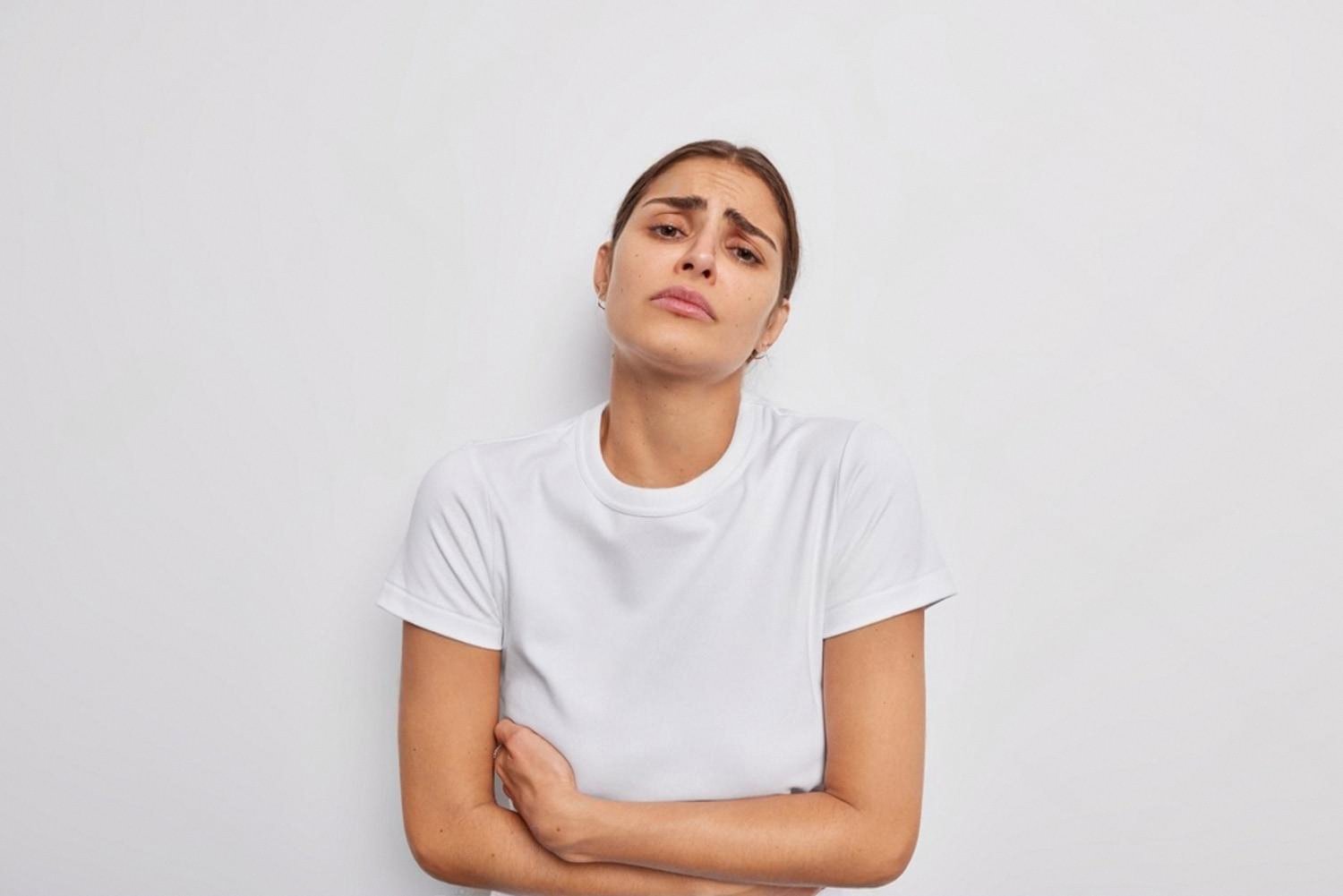Young woman holding her stomach with fatigue, a common sign of IBD flare-ups